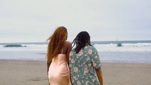 妇女夫妇牵着手在沙滩上散步 · 免费素材视频