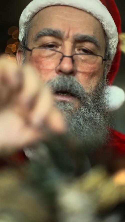 一名老人打扮成圣诞老人吹圣诞树装饰 · 免费素材视频