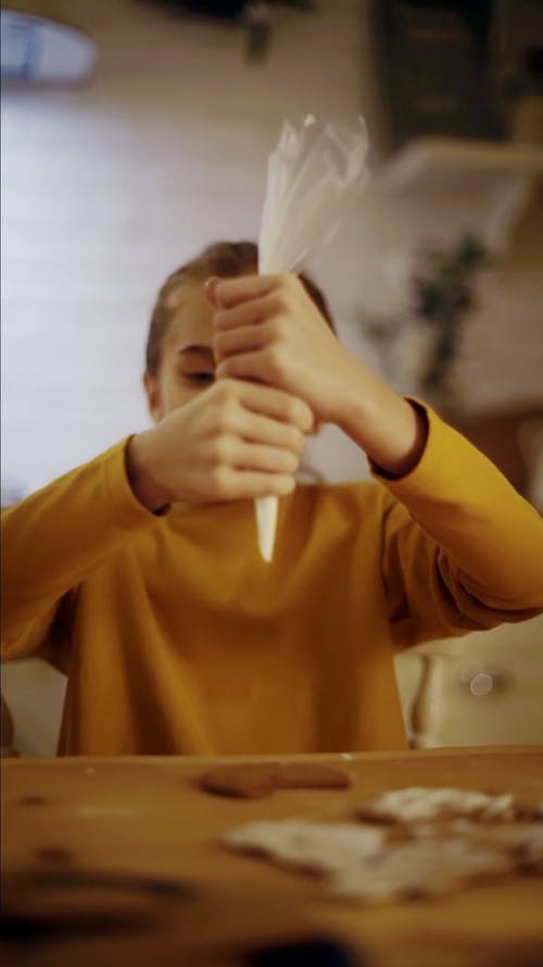 一个女孩用糖霜管袋装饰饼干 · 免费素材视频