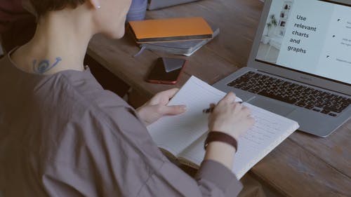 一个女人在笔记本电脑上的图表上写笔记 · 免费素材视频