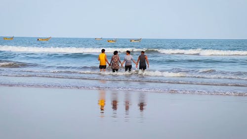 一群人手拉手站在海边，勇敢的海浪力量 · 免费素材视频