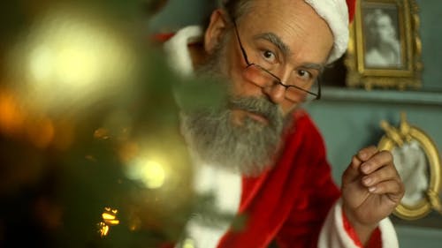 圣诞老人在一棵圣诞树后面偷看 · 免费素材视频