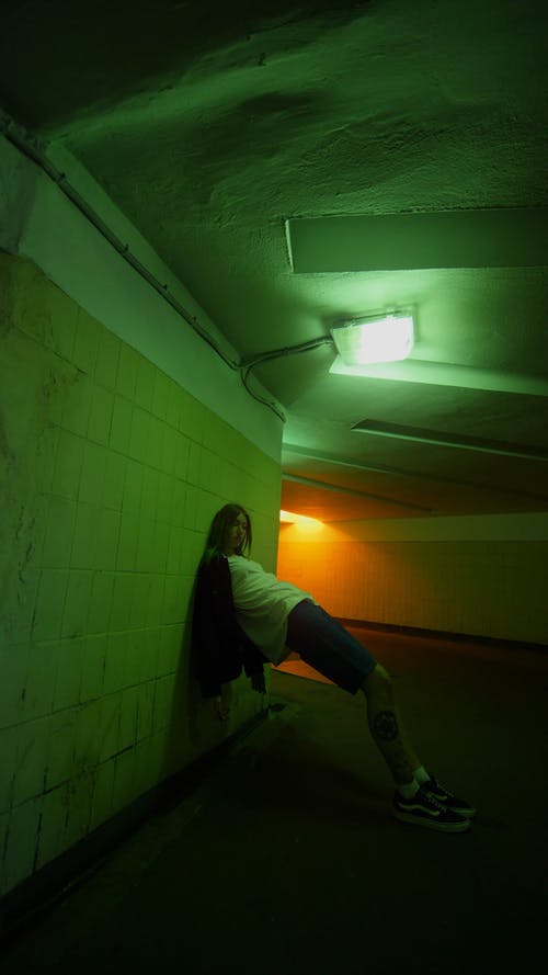 一个年轻的女子，倚在地下通道的墙上 · 免费素材视频