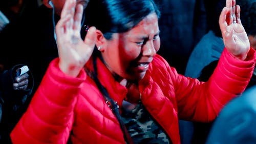 一个穿着红色夹克的女人在宗教活动中敬拜时哭泣 · 免费素材视频