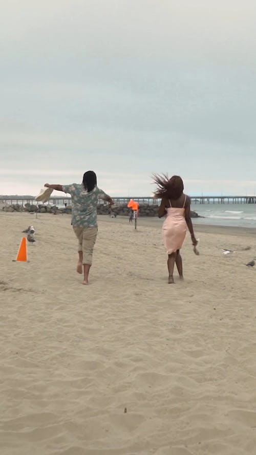 一对夫妇在沙滩上跑的背面 · 免费素材视频