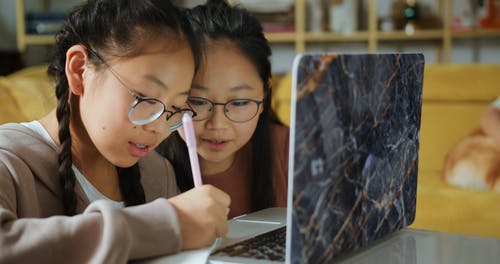 两个孩子开心交谈，看着一台笔记本电脑 · 免费素材视频