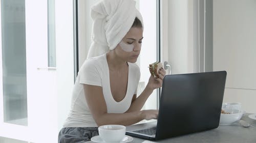 一个女人在用笔记本电脑工作时吃早餐 · 免费素材视频