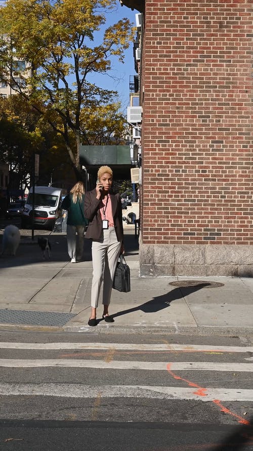 一个女人在她的手机过马路 · 免费素材视频
