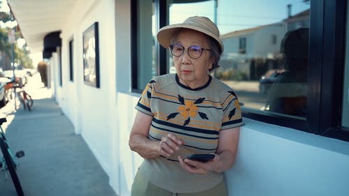 一名老妇在等待时使用她的手机 · 免费素材视频
