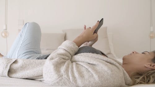 女人忙着躺在床上时使用她的智能手机 · 免费素材视频