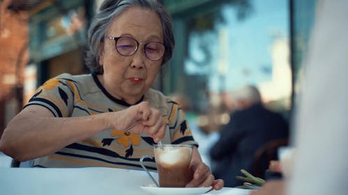 一名老妇在一家餐馆的室外坐吃 · 免费素材视频