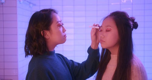 女人在她的妹妹上涂了眼影 · 免费素材视频