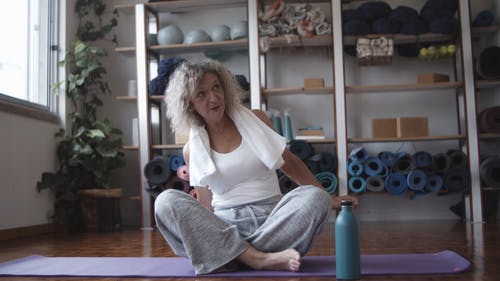 一名老妇坐在瑜伽垫上 · 免费素材视频