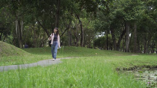 一个女人拿着她的智能手机在公园散步 · 免费素材视频