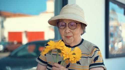 老妇闻到黄色的花朵 · 免费素材视频