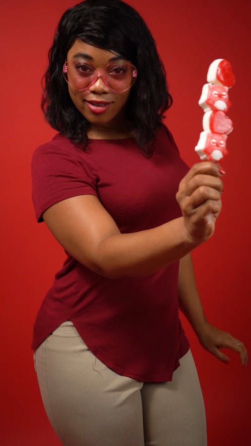 红色的衬衫，向相机展示棒棒糖的女人 · 免费素材视频